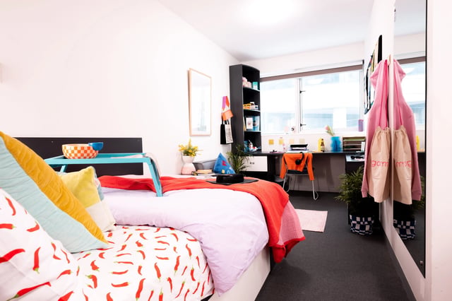 Bed with chili print desk chair and shelves bedroom at Scape Adelaide Central in Adelaide Student Accommodation