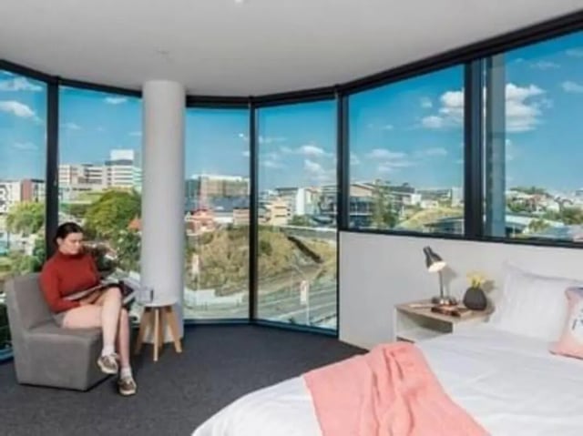 Woman reading in armchair near bed bedroom at Unilodge South Bank in Brisbane Student Accommodation