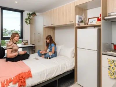 Two students on bed with fridge and kitchenette bedroom at Unilodge South Bank in Brisbane Student Accommodation