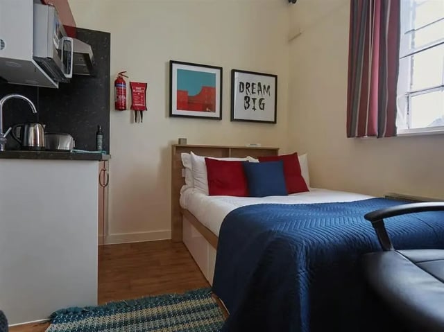 Bed with red and blue pillows fire extinguisher kitchen unit bedroom at Abbeygate in Chester Student Accommodation