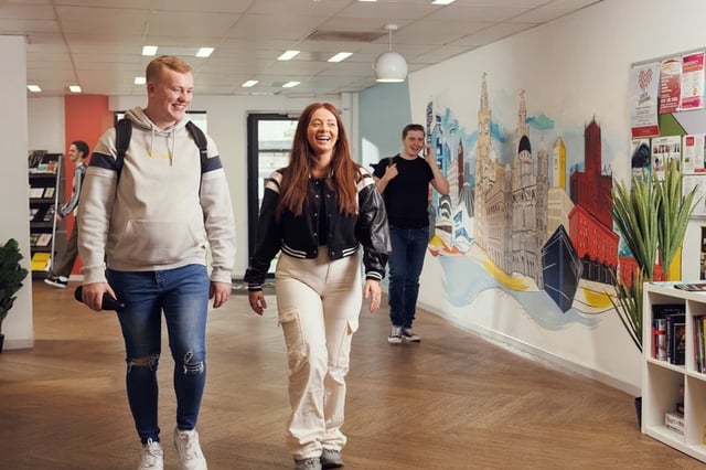 Students walking in hallway with city mural common area at Grand Central in Liverpool Student Accommodation