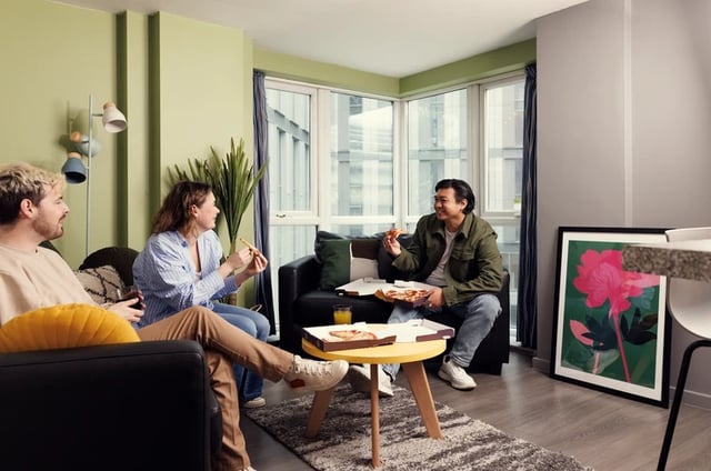 Students eating pizza on sofas living room at Grand Central in Liverpool Student Accommodation