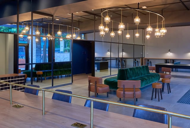 Green sofas leather chairs table and stools communal area at Cumberland Place in Southampton Student Accommodation