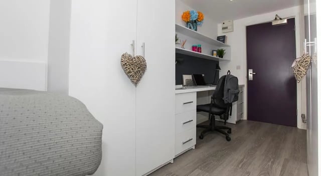 Wardrobe desk chair backpack and flowers study area at The Cube Ealing in London Student Accommodation