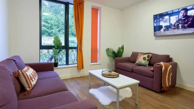 Purple sofas white coffee table television living room at The Village at The Viaduct in Durham Student Accommodation