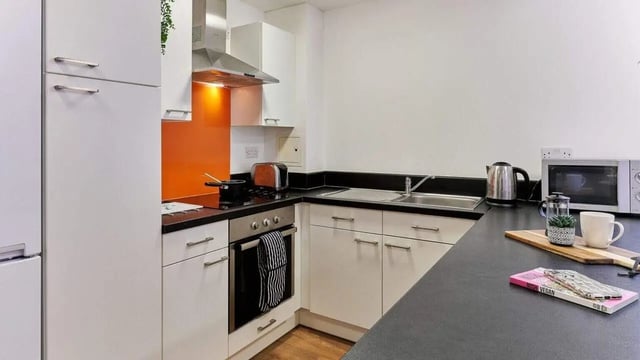 Modern white kitchen with appliances and orange backsplash kitchen at The Village at The Viaduct in Durham Student Accommodation