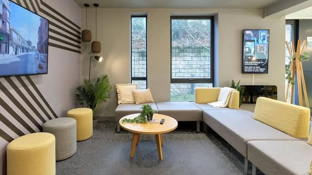 Modern lounge with gray sectional yellow stools living room at The Village at The Viaduct in Durham Student Accommodation