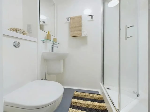 Toilet sink shower with towel and mat Bathroom at Straits Aire in Leeds Student Accommodation