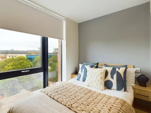 Bed with cushions and throw overlooking window bedroom at Straits Aire in Leeds Student Accommodation
