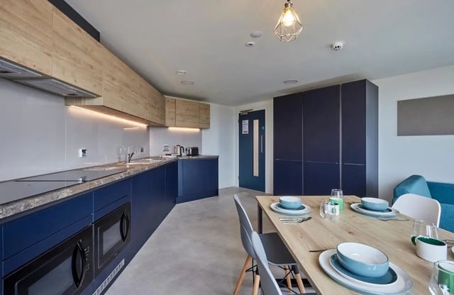 Blue cabinets microwaves and dining table kitchen at Regatta Place in Durham Student Accommodation