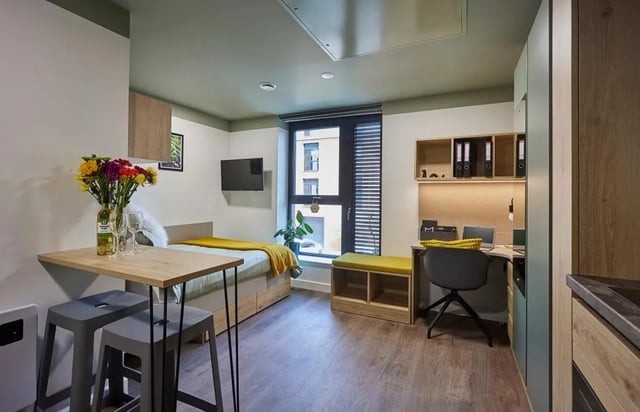 Bed desk with laptop and stools living room at Regatta Place in Durham Student Accommodation