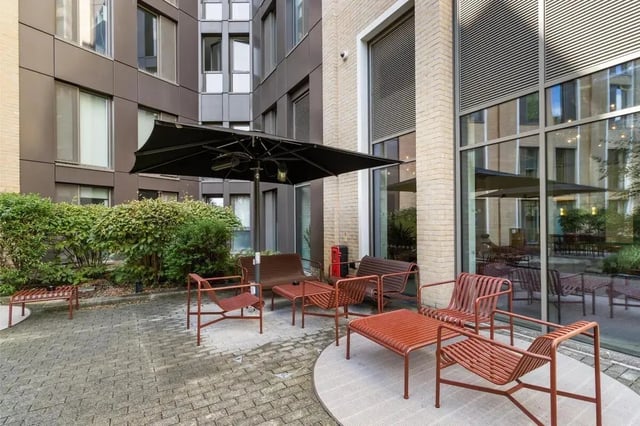 Outdoor seating with umbrella and greenery exterior at Chapter White City in London Student Accommodation
