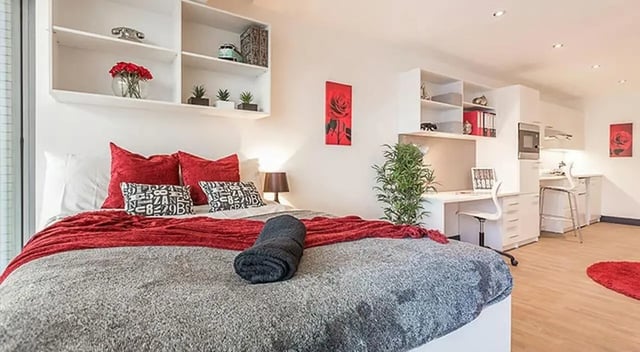 Bed with red blankets study area kitchen living room at Marland House in Southampton Student Accommodation