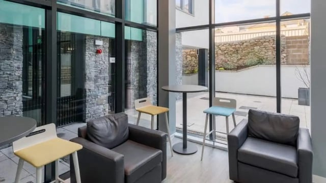 Chairs tables and stone walls common area exterior at The Old Dairy in Plymouth Student Accommodation