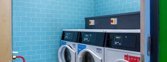 Washers with digital displays blue tiled wall laundry room at Element Manchester in Manchester Student Accommodation