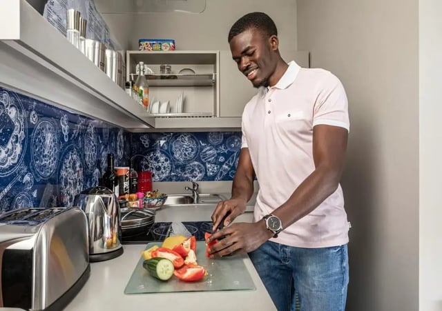 Man chopping vegetables on kitchen counter kitchen at Study Inn Talbot Street Nottingham in Nottingham Student Accommodation