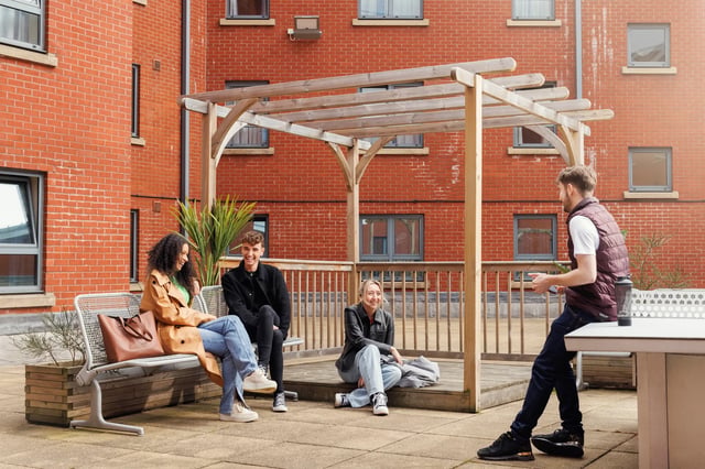Students relaxing on bench and floor outdoor patio exterior at Archways in Sheffield Student Accommodation