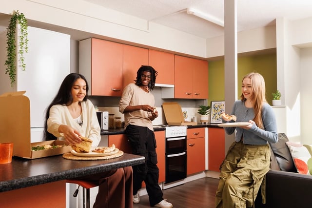 Students eating pizza in a shared kitchen at Archways in Sheffield Student Accommodation