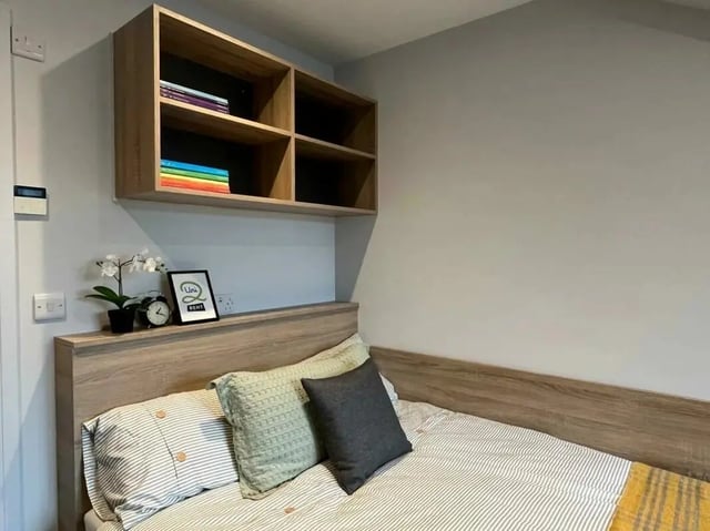 Bed with pillows shelf with books and decor bedroom at Commercial Point Nottingham in Nottingham Student Accommodation