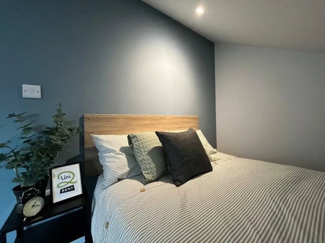 Bed with striped duvet wood headboard pillows bedroom at Commercial Point Nottingham in Nottingham Student Accommodation