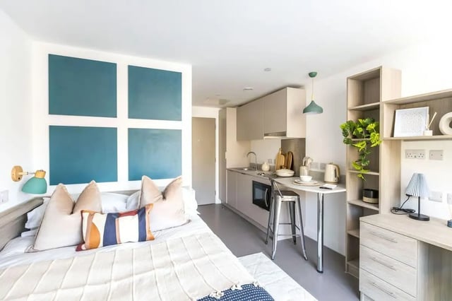 Bed with pillows kitchen counter and shelves studio apartment at Timber Yard in Bristol Student Accommodation