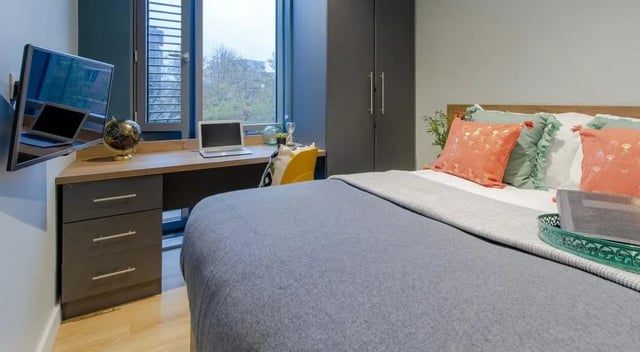Bed with desk television globe laptop and pillows bedroom at Crown House in Sheffield Student Accommodation
