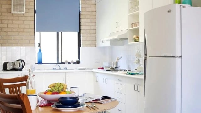 Kitchen with white cabinets table fruit bowl refrigerator kitchen at UniLodge SCU Coffs Harbour in Coffs Harbour Student Accommodation