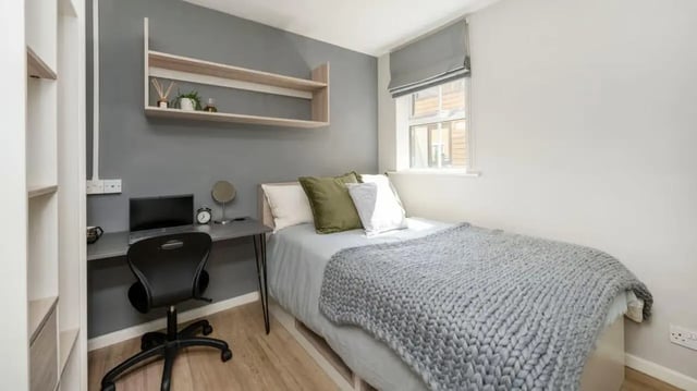Desk with laptop bed with grey blanket bedroom at Emily Davies in Southampton Student Accommodation