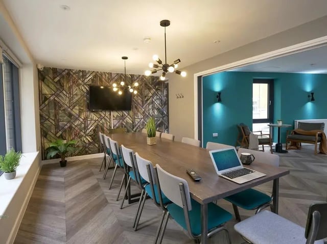 Long table chairs laptop plants tv common area at Emily Davies in Southampton Student Accommodation