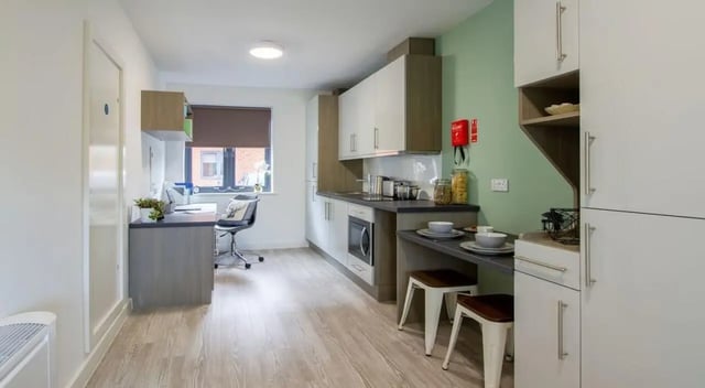 Desk chair cabinets microwave and stools kitchen at St Giles Studios in Durham Student Accommodation