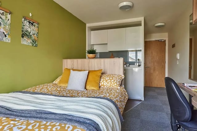 Bed with yellow pillows kitchen area desk bedroom at Selly Oak Court in Birmingham Student Accommodation
