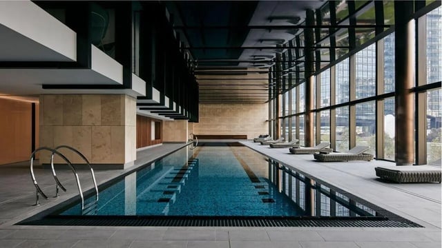 Indoor swimming pool with loungers and city view at West Tower, Melbourne Quarter in Melbourne Student Accommodation