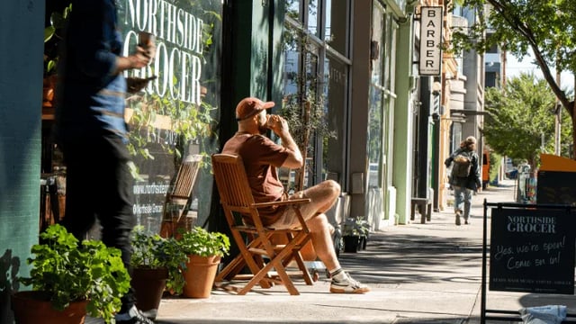 Man drinking coffee on wooden chair exterior at WeAreLiving Preston in Melbourne Student Accommodation