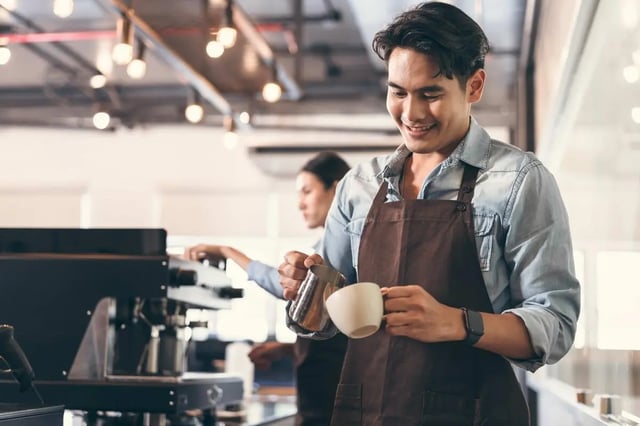 Barista pouring milk into coffee cup work area at Indi Footscray in Melbourne Student Accommodation