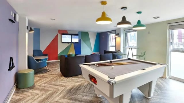Pool table blue chairs geometric wall tv living area at Frobisher House in Plymouth Student Accommodation