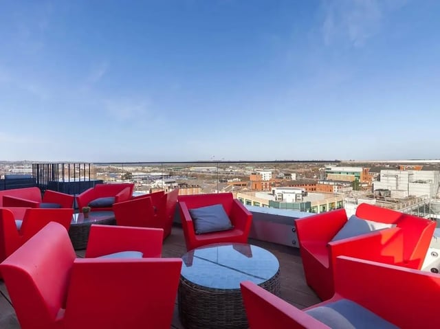 Red chairs and tables on a rooftop terrace exterior at Central Studios Reading in Reading Student Accommodation