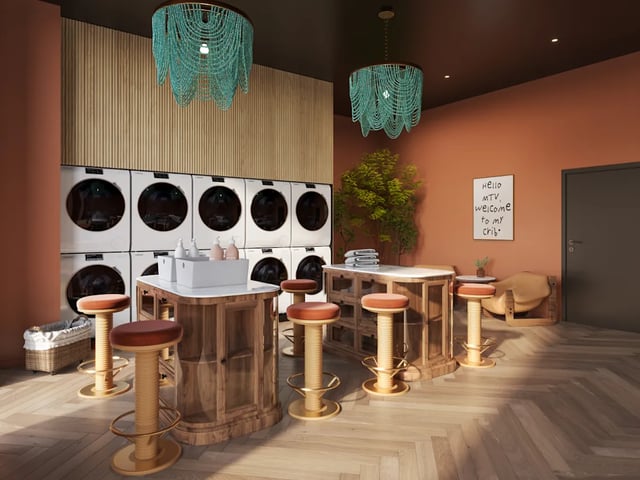 Row of washing machines with bar stools laundry area at Biscuit Factory in Belfast Student Accommodation