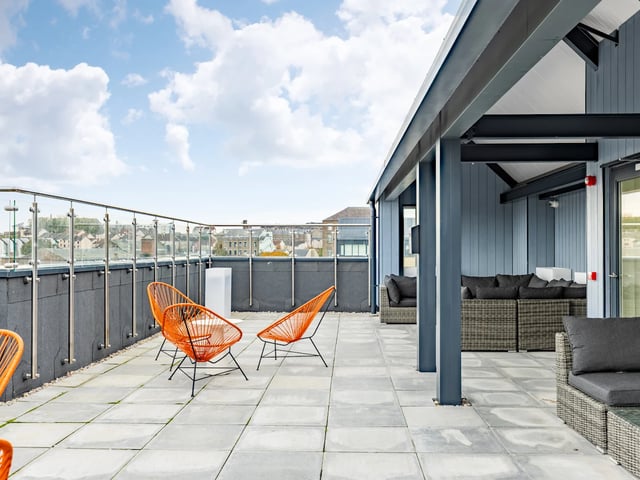 Orange chairs grey sofas rooftop lounge area exterior at Stanley Studios - Dundee in Dundee Student Accommodation