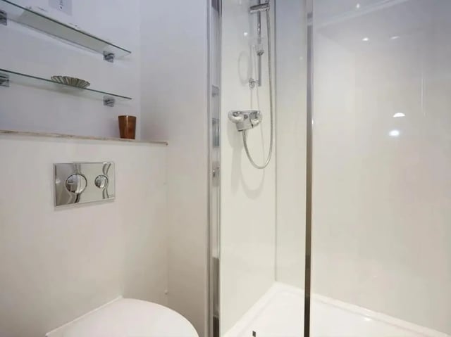 Toilet shower shelves and cup bathroom at Woodside House in Glasgow Student Accommodation