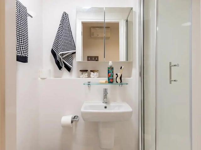 Sink cabinet mirror towels toiletries shower enclosure bathroom at Glassworks in Bristol Student Accommodation