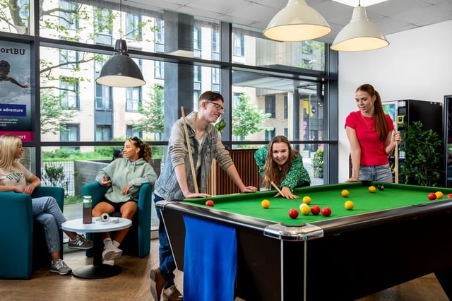 Students play pool in a common area living room at Purbeck House in Bournemouth Student Accommodation