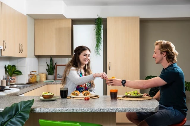 Couple eating burgers in kitchen kitchen at Purbeck House in Bournemouth Student Accommodation