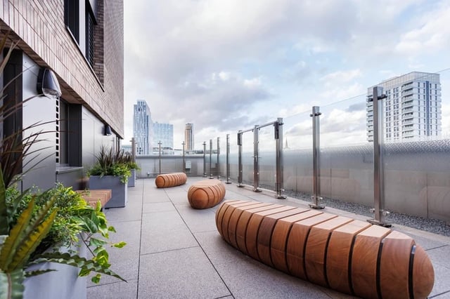 Wooden benches glass railing and city view outdoor area at Hayloft Point in London Student Accommodation
