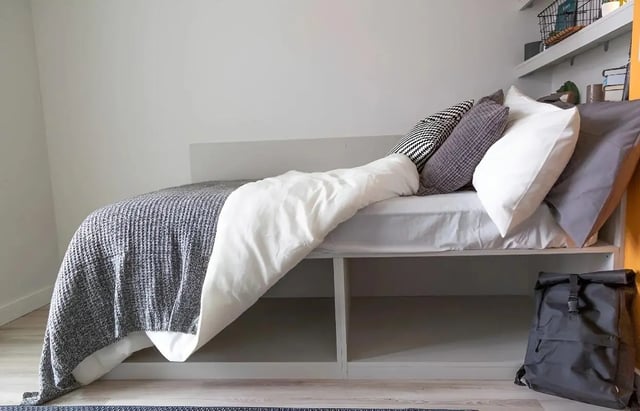 Bed with pillows storage shelves backpack bedroom at 123 York Street in Belfast Student Accommodation