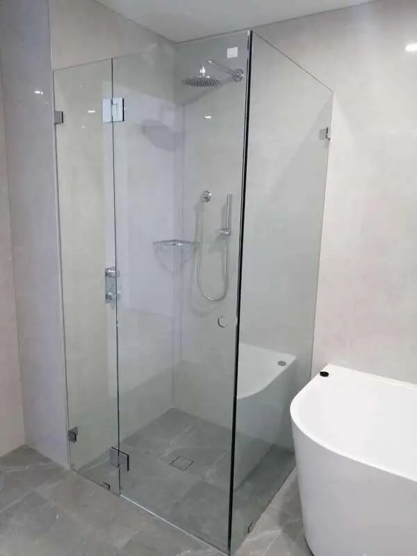 Glass shower enclosure with seat bathtub bathroom at Belong Macquarie in Sydney Student Accommodation