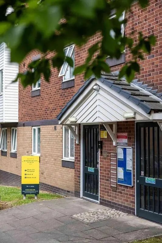 Brick building with black doors and sign exterior at Woodhouse Flats in Leeds Student Accommodation