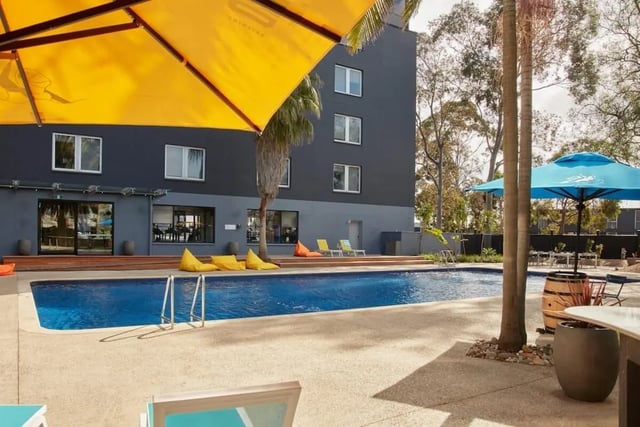 Pool lounge chairs umbrellas and building exterior at Campus Melbourne in Melbourne Student Accommodation