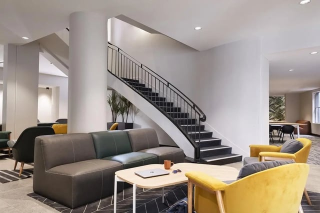 Modern lounge area with sofas chairs staircase living room at Campus Melbourne in Melbourne Student Accommodation