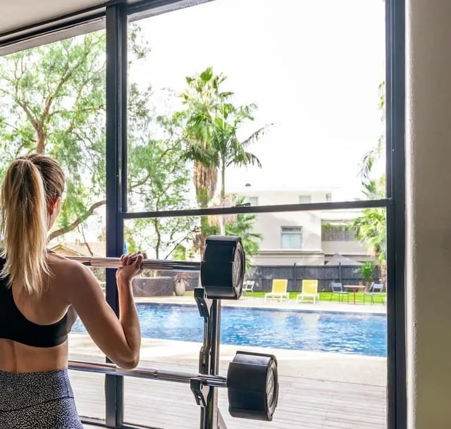 Woman lifting barbell by pool gym exterior at Campus Melbourne in Melbourne Student Accommodation