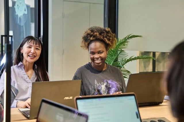 Students working at laptops at a communal table Study area at Campus Melbourne in Melbourne Student Accommodation